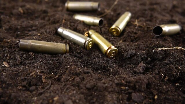 Bullet casings fall to the ground. Slow motion.