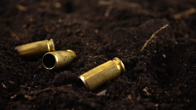 Bullet casings from a 5mm pistol fall to the ground. Slow motion.
