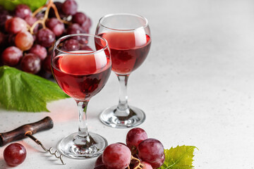 Two glasses of red wine and grapes and corkscrew on light background with tex space