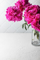 Bouquet of pink peonies on a white table. Minimalistic still life, summer background with copy space