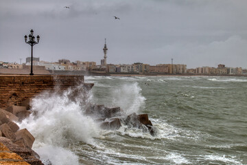 Waves breaking against the stone walls of the promenade of Cadiz, Spain