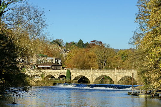 Autumn Foliage Around A Bridge Above A Dam On The River Avon In Bath, England, UK