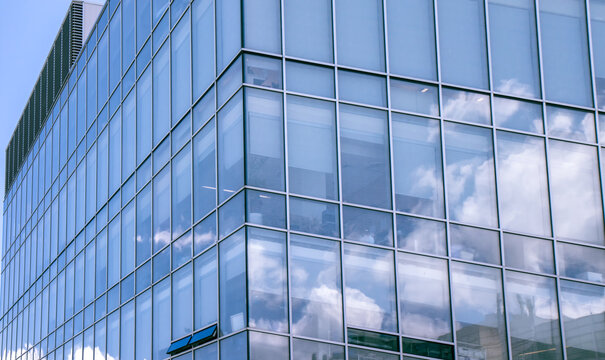Exterior view of multi-storey building showing clouds reflecting in blueish window glazing, aluminum mullions, daytime, nobody