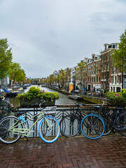 Fototapeta premium Amsterdam street with cycles, canal and beautiful Dutch buildings, Netherlands