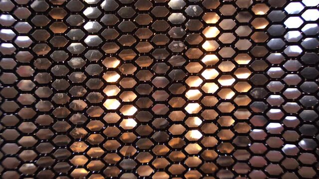 Metallic silver shinny sequin pattern texture bg with warm reflection, honeycomb shape, flashing lights