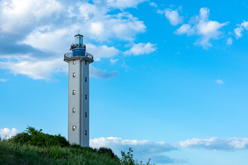 A beautiful sea lighthouse against a blue sky with clouds