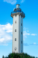A beautiful sea lighthouse against a blue sky with clouds