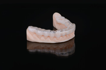Printed transparent dental cap made of polymer on a light colorful background. Dental splint against bruxism.