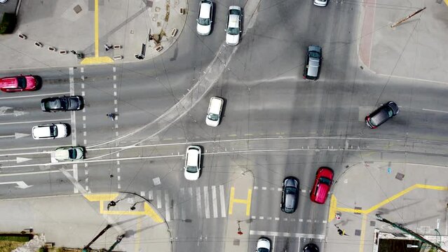 Aerial drone view of crossroad in the city. Cars and buses driving on asphalt street in town. Traffic on roads, view from above. Pedestrians cross the street.	
