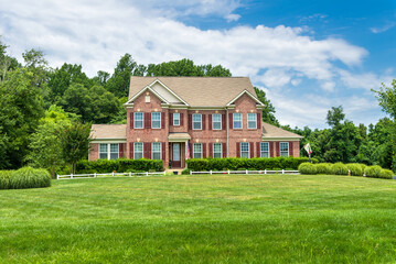 Fototapeta na wymiar large traditional red brick colonial house on a green lawn in Virginia.