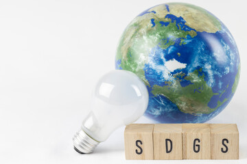 SDGsの文字と地球儀と電球。SDGsのイメージ