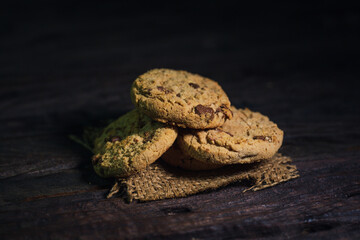 Chocolate chip cookies on linen napkin in white plate on wooden table. Stacked chocolate chip cookies close up.