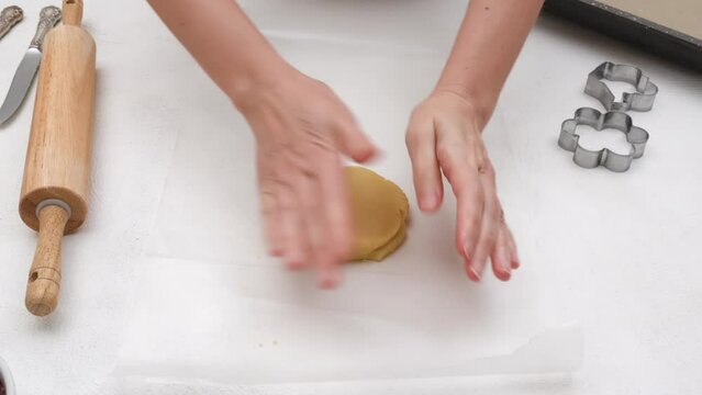 Flower shaped shortbread cookies filled with raspberry jam recipe. Woman hands rolling cookie dough on kitchen table