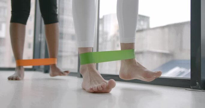 Close up woman and trainer with resistance bands on legs