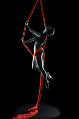 Young woman gymnast with red gymnastic aerial silks