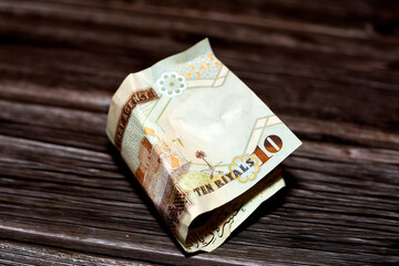 Folded Saudi Arabia money of 10 SAR ten riyals isolated on wooden background, Crumpled 10 Saudi...