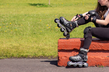 Sporty young woman stretching and resting after skating in a park on a sunny day