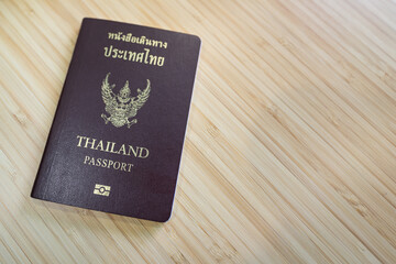 Thai citizen passport (Thai and English text are same meaning) is placed on wooden table. Ready for travel concept scene.