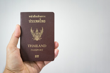 Thai citizen passport (Thai and English text are same meaning) is holding by hand on white background with copy space. Ready for travel concept scene.