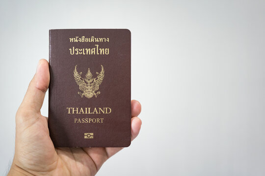 Thai citizen passport (Thai and English text are same meaning) is holding by hand on white background with copy space. Ready for travel concept scene.