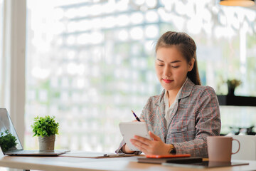 Obraz premium Asian business woman working on laptop computer in her workstation, startup, businessperson, employee, marketing concept, account, online finance, ecommerce, freelance.