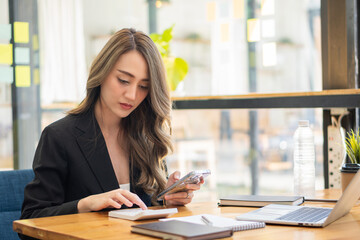 Happy woman working using multiple devices on her desk at home. Executives working online with laptops and desktop phones at the office.