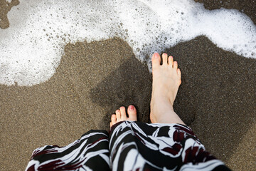 元名海岸の波打ち際で朝のお散歩をする女性の足元（千葉県鋸南町） - obrazy, fototapety, plakaty