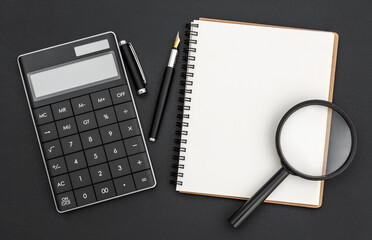 Notepad with calculator and magnifying glass. Business concept.