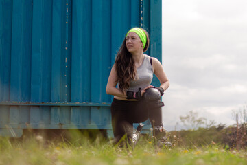 Sporty young woman stretching and resting after skating in a park on a sunny day
