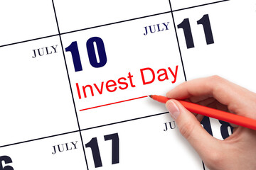 Hand drawing red line and writing the text Invest Day on calendar date July 10. Business and financial concept.