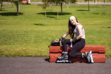 Fototapeta premium Sporty young woman stretching and resting after skating in a park on a sunny day