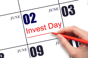Hand drawing red line and writing the text Invest Day on calendar date June 2. Business and...