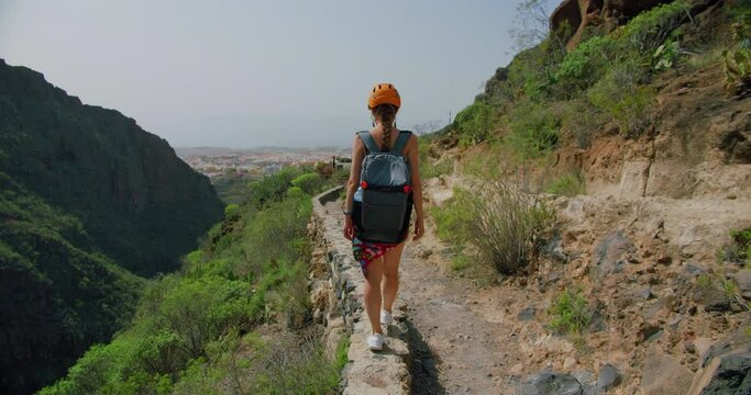 Woman tourist in a hemlet enjoying the view of gorge and mountains. Girl in active solo travel in Canary islands. Tenerife. Barranco del Infierno.