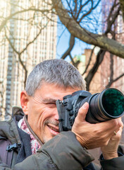 Male photographer in New York City, park and buildings on the background.