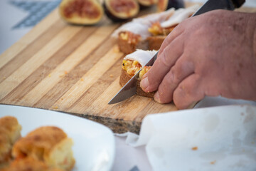 Elderly man spread fig jam on slices of bread outdoor.