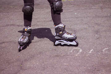 macro photography of some inline skates, and a woman using them on the asphalt on a sunny day