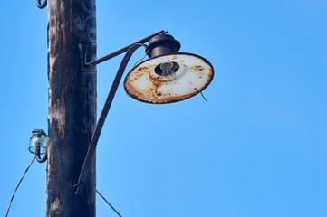 an old lantern is hanging on a wooden pole with a broken light bulb