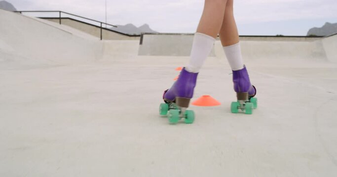 Closeup of female legs roller skating outside in a skate park. Skilled skater girl or person riding fast through cones. Swerving with vintage colorful roller skates practicing for sports competition