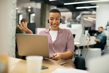 Happy black businesswoman talking during video call via laptop in office.