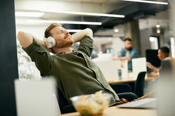 Relaxed businessman wearing headphones and enjoying in music with is eyes closed.