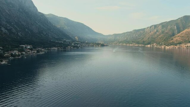 Montenegro. Adriatic Sea. Bay of Kotor. Popular tourist spot. Village on the coast. Houses with orange tiled roofs. Summer. Tourist season. Drone. Fly. Aerial view. The camera moves from left to right