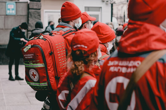 Kyiv, Ukraine - Jun 25, 2022: A crowd of emergency medic assistants in red uniforms with backpacks stand outdoor on the street. Aid. Emergency. Medic. Profession. Safety. Service. Teamwork. War. Cross