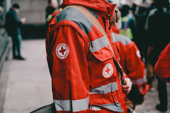 Kyiv, Ukraine - Jun 25, 2022: A crowd of emergency medic assistants in red uniforms with backpacks stand outdoor on the street. Victim. Volunteer. Working. First Aid. Work. Care. Event. Emblem. Nurses