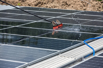 Worker Cleaning solar panels with brush and water. Worker cleaning solar modules in a Solar Energy...