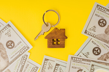 Home key with a small house and dollar banknotes top view. The concept of renting or selling house or flat, mortgage, investment or real estate, property buying