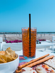 Close up shot of a glass of Spritz, italian aperitif, and complimentary snack, potato crisps,...