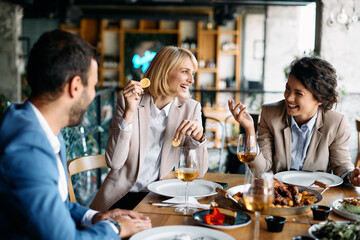 Cheerful colleagues laugh and have fun during business lunch in restaurant.