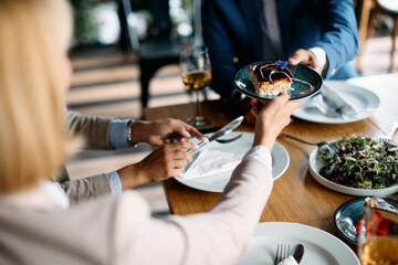 Close up of business people having cake for dessert after lunch in restaurant.