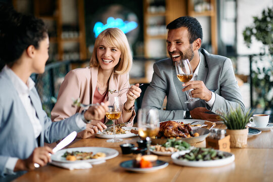 Cheerful coworkers talk and have fun during business lunch in restaurant.