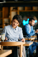 Young businesswoman reads notes during her coffee break in cafe.